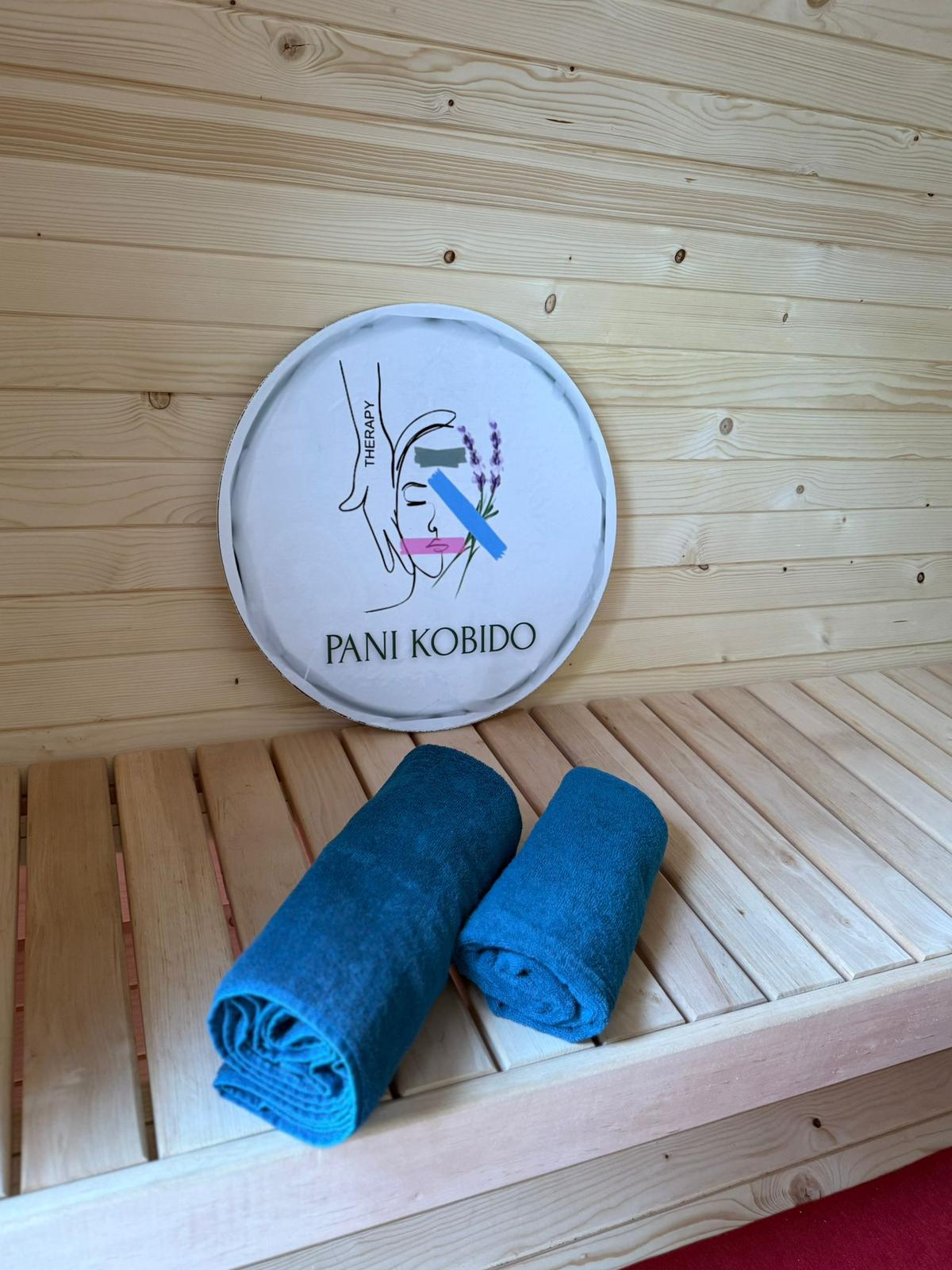 Ława w saunie z ręcznikami i logo Pani Kobido